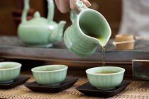 Main féminine verser le thé dans des tasses à thé — Photo de stock