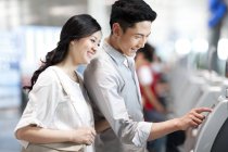 Китайская пара пользуется билетным автоматом в аэропорту — стоковое фото
