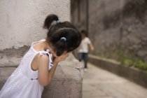 Mädchen guckt beim Versteckspiel hinter die Ecke — Stockfoto