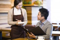 Chinesische Kellnerin nimmt Bestellung von Mann in Coffeeshop an — Stockfoto