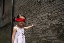 Китаянка с повязкой на глазах играет в прятки в переулке — стоковое фото