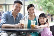 Família chinesa sentada no café da calçada com bebidas frias — Fotografia de Stock