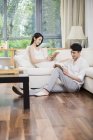 Young Chinese couple reading books in living room — Stock Photo