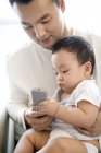 Homem chinês com criança segurando controle remoto — Fotografia de Stock