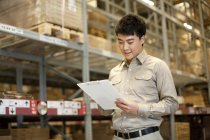 Male Chinese warehouse worker with clipboard — Stock Photo