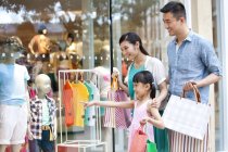 Chinese girl with family pointing at store window in shopping mall — Stock Photo