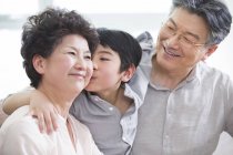 Neto chinês abraçando avós e beijando avó — Fotografia de Stock