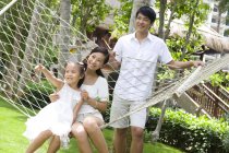 Chinese parent with daughter resting in hammock — Stock Photo