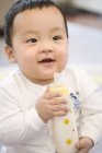 Portrait of Chinese infant with milk bottle — Stock Photo