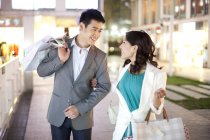 Young Chinese couple shopping in evening city — Stock Photo