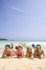 Chinese friends lying with scuba masks at beach sand — Stock Photo