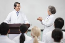 Medical workers clapping at seminar to senior man — Stock Photo