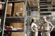 Male and female Chinese workers talking in warehouse — Stock Photo