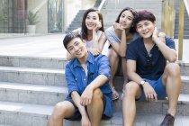 Chinesische Freunde auf Treppen und schauen in die Kamera — Stockfoto