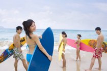Китайские друзья стоят с досками для серфинга на пляже Хайнань — стоковое фото