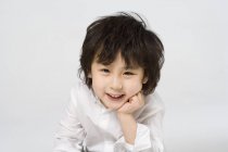 Portrait of little Asian boy with hand on chin on gray background — Stock Photo