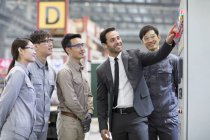 Businessman and Asian engineers talking at factory — Stock Photo