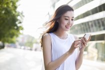 Chinesin blickt auf Straße auf Smartphone herab — Stockfoto