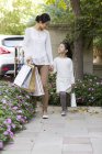 Chinese mother and daughter walking together with shopping bags — Stock Photo