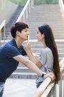 Mujer china poniendo smartphone para beso novio - foto de stock