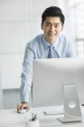 Uomo d'affari cinese in piedi al computer in ufficio — Foto stock