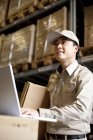 Male Chinese warehouse worker using laptop — Stock Photo