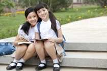 Schoolgirls sitting on steps with books and smiling — Stock Photo