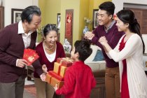 Niño pequeño con padres visitando a abuelos con regalos durante el Año Nuevo Chino - foto de stock