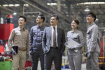 Homme d'affaires chinois mature et équipe d'ingénieurs posant à l'usine — Photo de stock