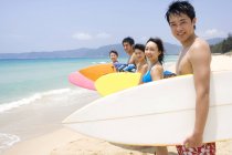 Amigos chinos de pie con tablas de surf en la playa de Hainan - foto de stock