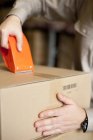 Close-up of male warehouse worker packing box — Stock Photo