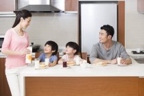 Família chinesa tomando café da manhã na cozinha — Fotografia de Stock