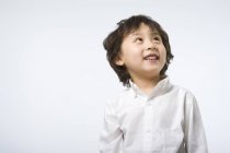 Portrait of little Asian boy looking up on gray background — Stock Photo