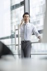 Chinese businessman talking on phone in doorway at office — Stock Photo