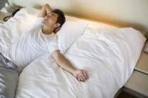 Chinese man lying on bed and looking up — Stock Photo