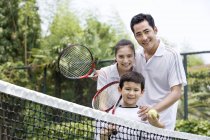 Китайская семья на теннисном корте с ракетками — стоковое фото