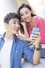Chinese couple using smartphone together and listening music — Stock Photo