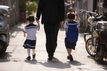 Father holding hands with children while walking on street, rear view — Stock Photo