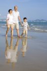 Chinesische Großeltern und Enkel laufen am Strand entlang — Stockfoto
