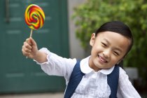 Chinese schoolgirl holding lollipop on street — Stock Photo