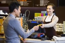Cliente chino pagando con tarjeta de crédito en cafetería - foto de stock