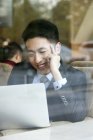 Hombre de negocios chino usando el ordenador portátil en la cafetería - foto de stock