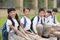Chinese schoolchildren sitting on floor at school yard — Stock Photo