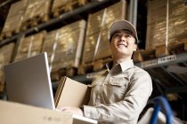Male Chinese warehouse worker using laptop — Stock Photo