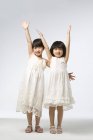 Retrato de meninas chinesas com braços levantados em fundo cinza — Fotografia de Stock
