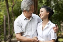 Senior Chinese couple holding hands and embracing in park — Stock Photo