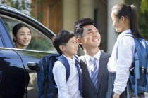 Padre chino y hermanos hablando delante del coche con la madre - foto de stock
