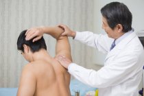 Médico chino senior dando masaje al paciente masculino - foto de stock