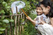 Crianças chinesas no jardim olhando para borboleta com rede de borboleta — Fotografia de Stock