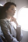 Femme d'affaires chinoise pensant dans l'avion — Photo de stock